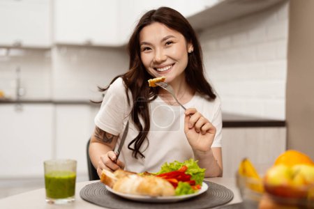 Foto de Mujer joven feliz disfrutando de una comida saludable en la cocina moderna. Atractiva ensalada de comida femenina, haciendo hincapié en el bienestar y el estilo de vida. - Imagen libre de derechos