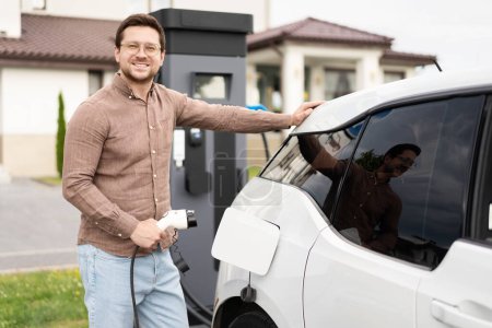 Homme recharge véhicule électrique à la maison