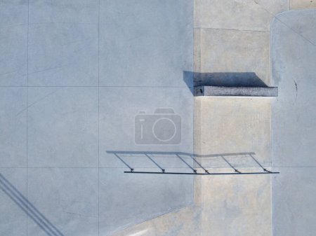 Photo for Aerial top view of sloped metal rails for grind tricks in an empty concrete skatepark - Royalty Free Image
