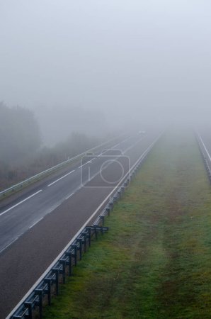 Foto de Un coche atraviesa la niebla en una autopista con poco tráfico - Imagen libre de derechos
