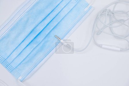 Photo for Minijack cable connection of a headphone and a surgical mask. White background - Royalty Free Image