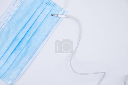 Photo for Face mask and mini jack connector from a smartphone headset. White background. - Royalty Free Image