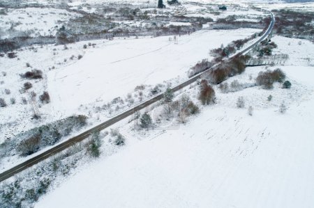 Téléchargez les photos : Drone vue aérienne d'une route dans un paysage enneigé - en image libre de droit