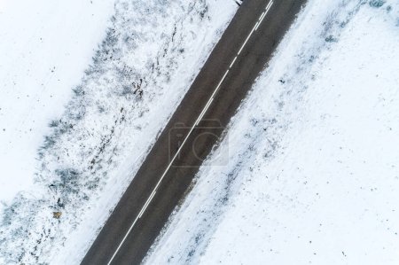 Téléchargez les photos : Vue aérienne d'un drone zénithal sur une route dans un paysage enneigé - en image libre de droit