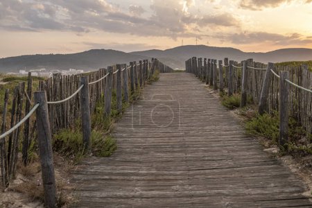 Sunrise view of a wooden walkway on the dunes of a beach