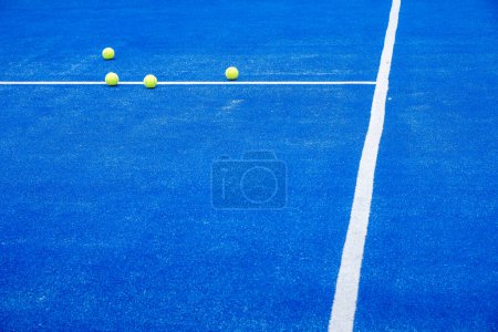 Selektiver Fokus. Blauer Paddle-Tennisplatz mit Kunstrasen und mehreren gelben Bällen.