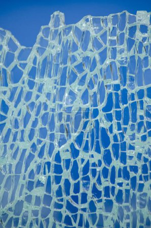 Nahaufnahme von Glasscherben, zersplittertem gehärtetem Glas auf blauem Hintergrund
