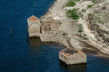 ruins of houses of an old flooded village, emerging from the drought. Climate change concept