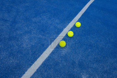 Foto de Tres pelotas de pádel en una cancha de césped artificial azul cerca de la línea central. Enfoque selectivo - Imagen libre de derechos