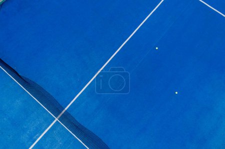 aerial drone view of a blue paddle tennis court with balls on its surface