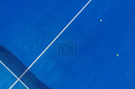 aerial drone shot of a blue paddle tennis court with balls on its surface