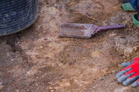 Die verschwommene Hand eines Archäologen mit rotem Handschuh, Kohlenhaufen und Korb. Arbeitswerkzeuge
