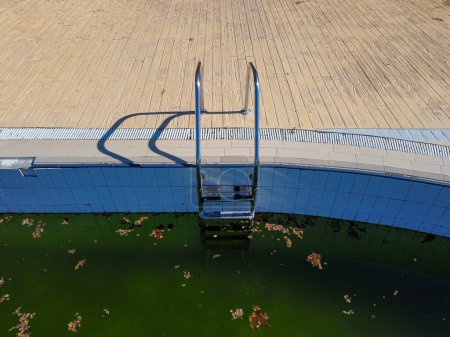 Luftaufnahme eines Schwimmbades mit grünem Wasser im Herbst