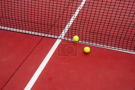 zwei Bälle neben dem Netz eines Tennisplatzes
