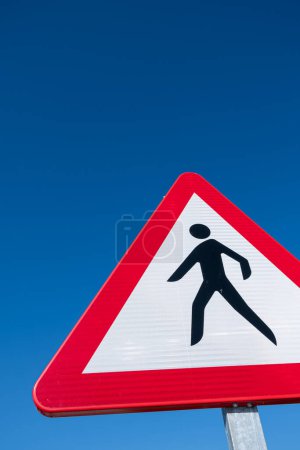 Dangerous pedestrian crossing traffic sign over a blue sky