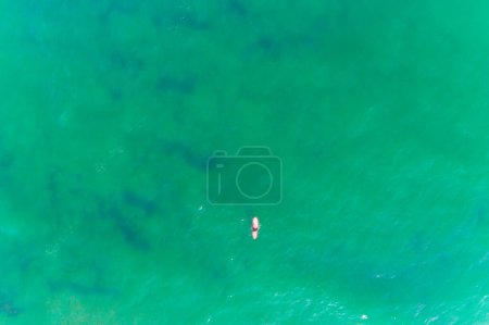 Téléchargez les photos : Drone vue aérienne d'un surfeur avec une planche de surf rouge dans une mer d'eau turquoise - en image libre de droit