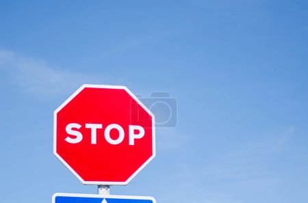 isolated stop sign with blue sky background, road safety
