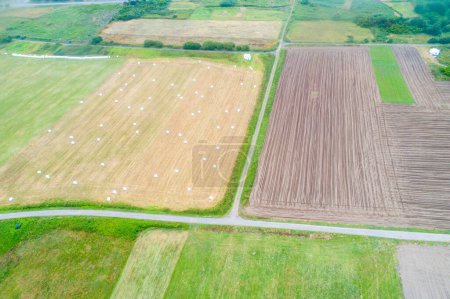 aerial view of agricultural fields, one field plowed for planting and another harvested with circular straw bales