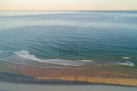 Drohnenaufnahme eines Strandes, des Meeres und des Horizonts bei Sonnenaufgang während der goldenen Stunde