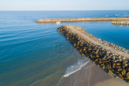 drone aerial view of a ship sailing from a breakwater protected harbor