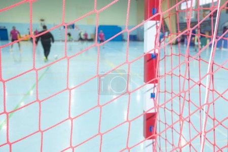 selective focus, netting of an indoor soccer goal with the players of the match out of focus in the background