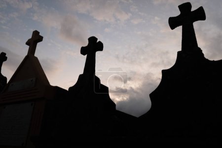silhouette of grave crosses in a catholic cemetery at dusk