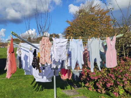 Laver les vêtements de bébé séchant sur une ligne rotative au soleil. Les tâches ménagères de la vraie vie - utiliser moins d "énergie pour sauver la planète.