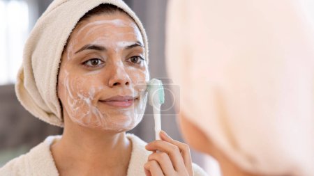 Schönheits-, Hautpflege- und People-Konzept - lächelnde junge Frau in der Hautpflege und Spiegelung im heimischen Badezimmer