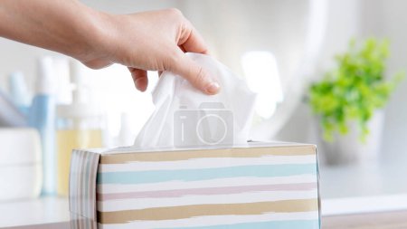 Photo for Women hand picking napkin tissue paper from the tissue box - Royalty Free Image