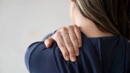 Foto de Vista trasera de una mujer que sufre de dolor en el hombro - Imagen libre de derechos