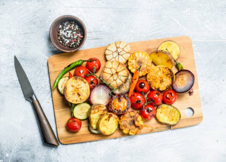 Grilled vegetables with spices and herbs on a cutting Board. On a rustic background.