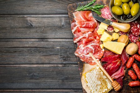 Photo for Antipasto background. Assortment of meat snacks on the Board with olives and Parmesan. On a wooden background. - Royalty Free Image