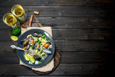 Foto de Comida mediterránea. Espaguetis de mariscos con almejas y vino blanco. Sobre un fondo de madera
. - Imagen libre de derechos