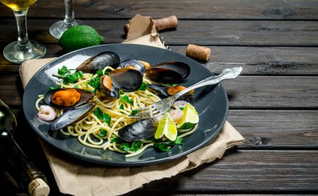 Foto de Comida mediterránea. Espaguetis de mariscos con almejas y vino blanco. Sobre un fondo de madera
. - Imagen libre de derechos