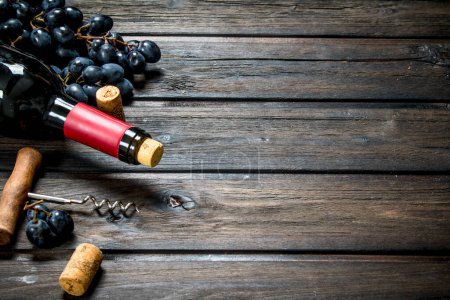 Téléchargez les photos : Bouteille de vin rouge avec des raisins. Sur un fond en bois
. - en image libre de droit