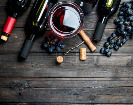Téléchargez les photos : Fond de vin. Vin rouge avec raisins et tire-bouchon. Sur un fond en bois
. - en image libre de droit