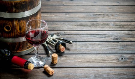 Wine background. A barrel of red wine with a corkscrew. On a wooden background.