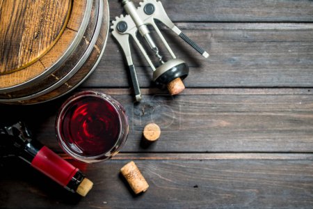 Wine background. A barrel of red wine with a corkscrew. On a wooden background.