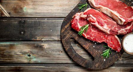 Photo for Raw marbled beef steaks with salt and aromatic spices. On a wooden background. - Royalty Free Image