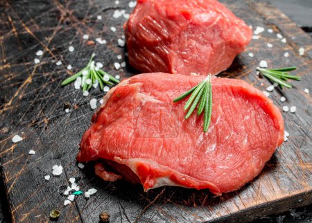Photo for Raw meat. Pieces of fresh beef with salt and rosemary. On a wooden background. - Royalty Free Image