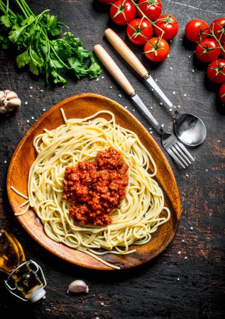 Spaghetti with Bolognese sauce in a plate with tomatoes, parsley and garlic. On rustic background Poster 657779994
