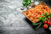 Spaghetti with Bolognese sauce on a plate with herbs, tomatoes and garlic. On rustic background Poster #657780276