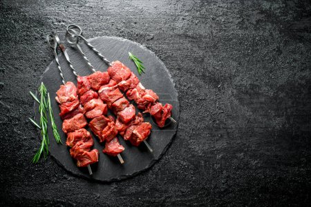 Kebab crudo con romero. Sobre fondo rústico negro
