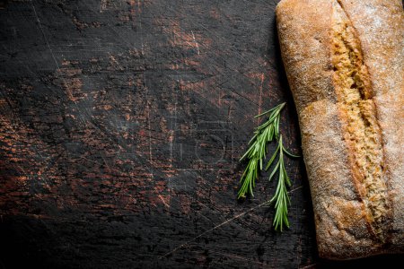 Téléchargez les photos : Ciabatta au pain au romarin. Sur fond rustique sombre - en image libre de droit