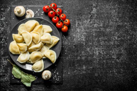 Foto de Dumplings con champiñones, tomates y hoja de laurel. Sobre fondo rústico oscuro - Imagen libre de derechos