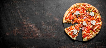 Téléchargez les photos : Tranches de pizza croustillante avec tomates, poivrons et champignons. Sur fond rustique sombre - en image libre de droit