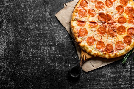 Téléchargez les photos : Pizza pepperoni aux saucisses et au fromage. Sur fond rustique sombre - en image libre de droit