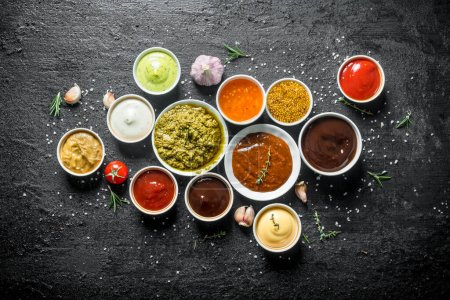 Photo for Set of sauces - tomato sauce, pesto, mustard, barbecue sauce, guacomole, mayonnaise. On black rustic background - Royalty Free Image