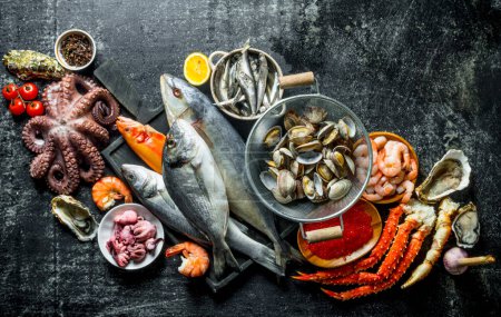 Fisch, Krabben, Austern, Garnelen und Kaviar auf dunklem rustikalem Hintergrund