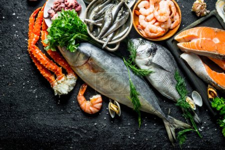 Téléchargez les photos : Steak de saumon sur une planche à découper avec des fruits de mer. Sur fond rustique noir - en image libre de droit